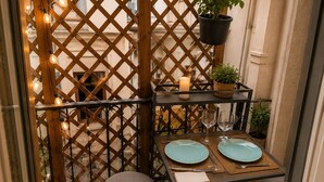 A small outdoor dining area with a table set for two, a candle, and a potted plant. - 16624498LIONS Le Suquet Old Town Forville Cozy Apartment (Cannes)