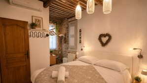 A bedroom with a bed, a wooden door, a stone wall, a heart-shaped decoration, and hanging lights. - 16624498LIONS Le Suquet Old Town Forville Cozy Apartment (Cannes)