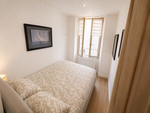 A bedroom with a bed, a window with blinds, a framed picture on the wall, and a door. - 16514416 LIONS La Croisette, just a stone's throw away (Cannes)