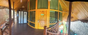 Interior de madera con una puerta central, una escalera y vistas al exterior.