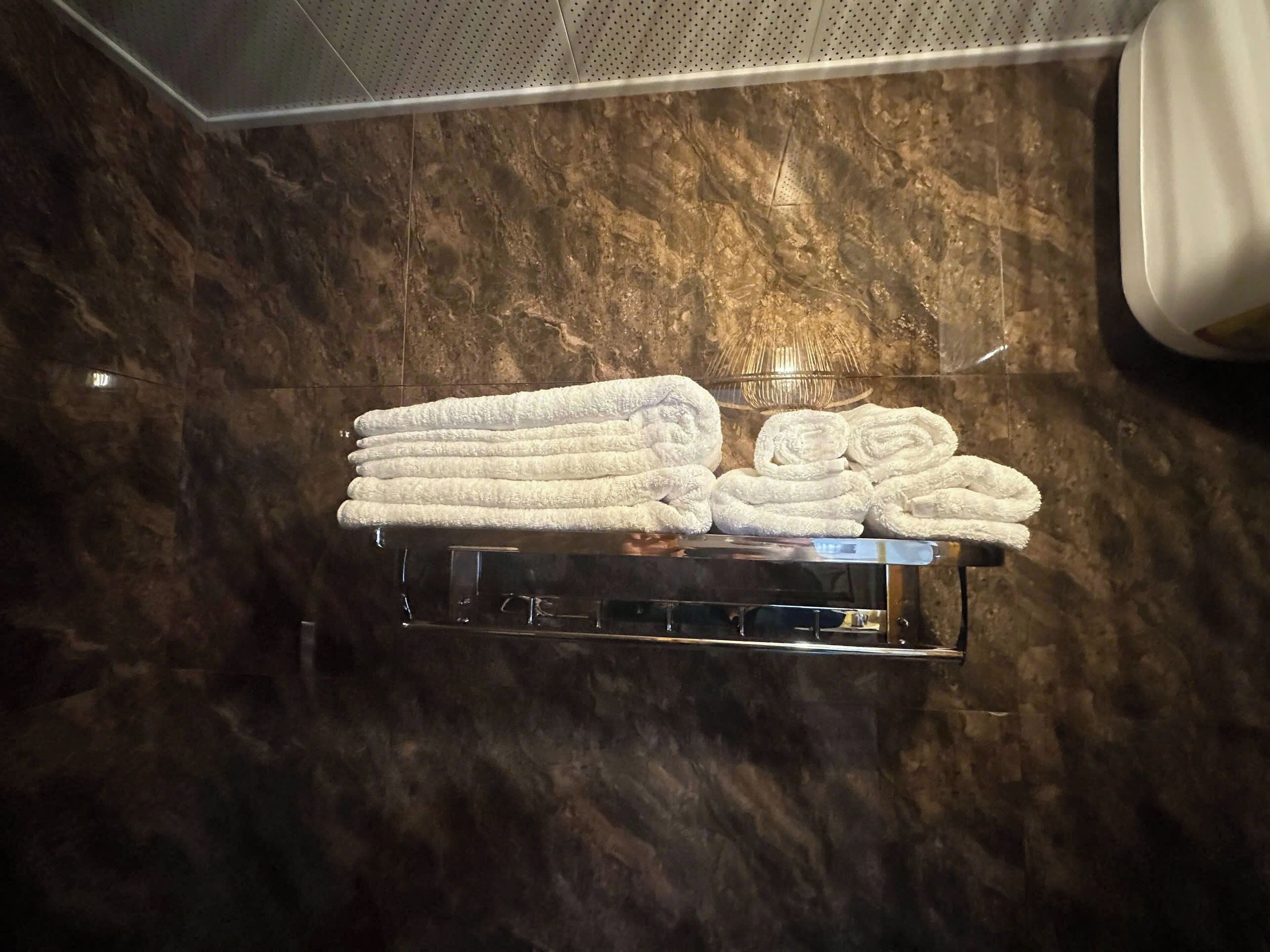 A marble wall with a towel rack holding neatly folded towels.
