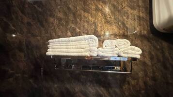 A marble wall with a towel rack holding neatly folded towels.