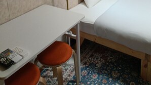 A hotel room with a bed, a desk, a chair, a lamp, a wall clock, and a window with curtains. - guest house mami (Taketa)