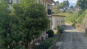 A residential building with a paved driveway and a tree in the foreground. - guest house mami (Taketa)
