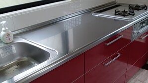 Una cocina con encimera de acero inoxidable, estufa a gas y un lavamanos.