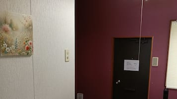 A hotel room with a dining table set, a painting on the wall, and a door with a sign.