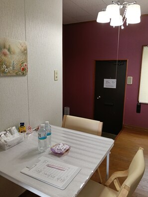 A hotel room with a dining table set, a painting on the wall, and a door with a sign.