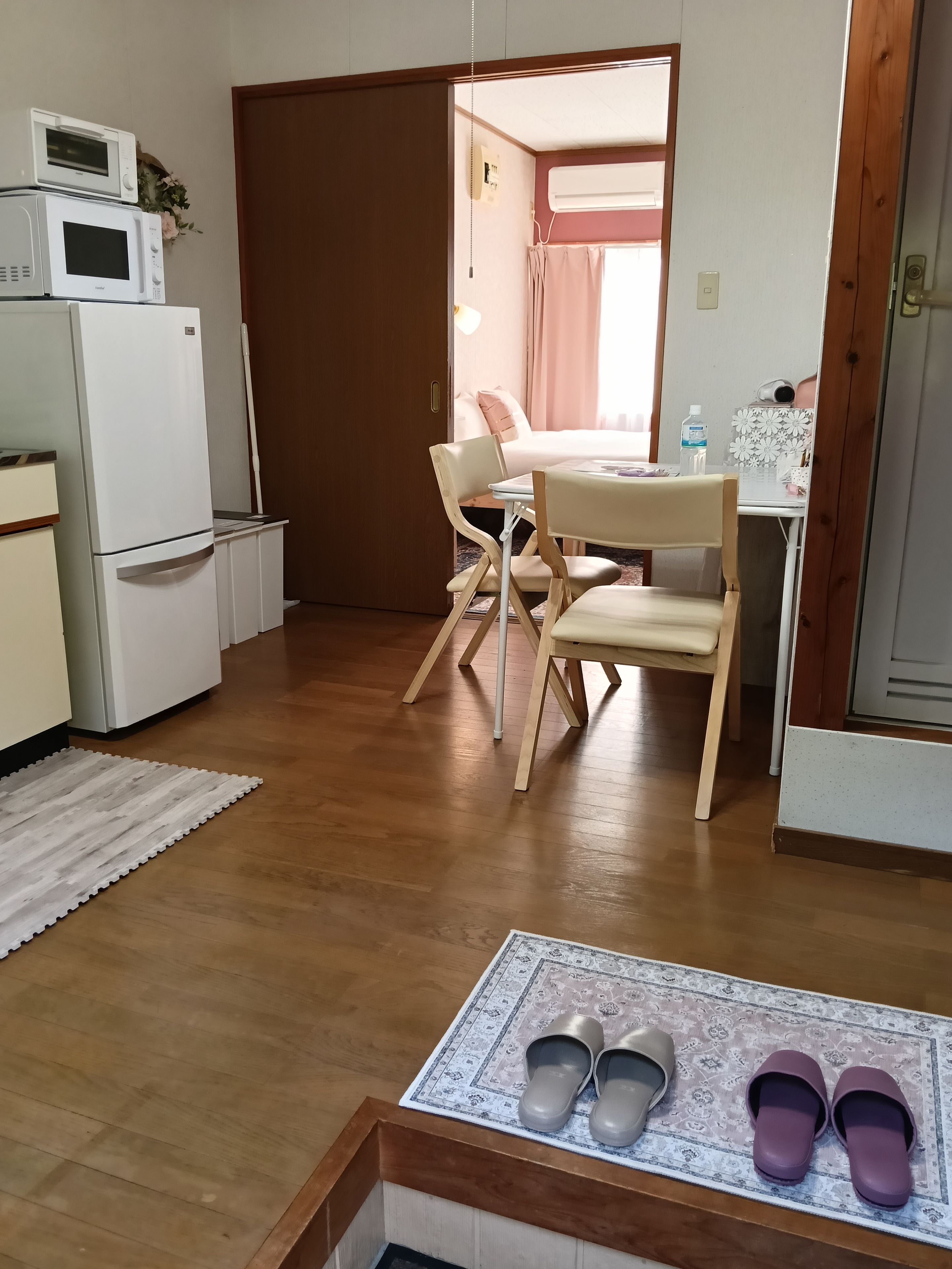 A compact kitchen with a refrigerator, microwave, and a small table with chairs.