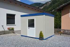 Ein kleines Gebäude mit einem Zimmer, mit weißer Fassade und blauen Verzierungen, einer Tür und einem Fenster.