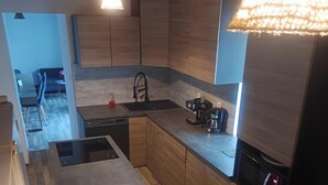 Eine moderne Küche mit Holzschränken, einem Einbauherd, einer Spüle und einer Kaffeemaschine.