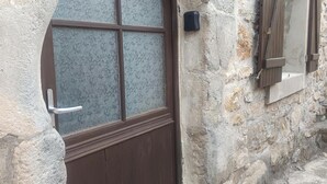 Ein Steinhaus mit einer Holztür und Fensterläden.