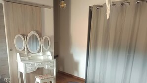 Ein Schlafzimmer mit einem Bett, einer Kommode mit Spiegeln, einem Sessel und einer Hängelampe.