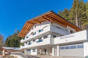 A modern multi-story building with a flat roof, large windows, and a garage. - Bergliebe Apartment TOP 1 (Gerlosberg)