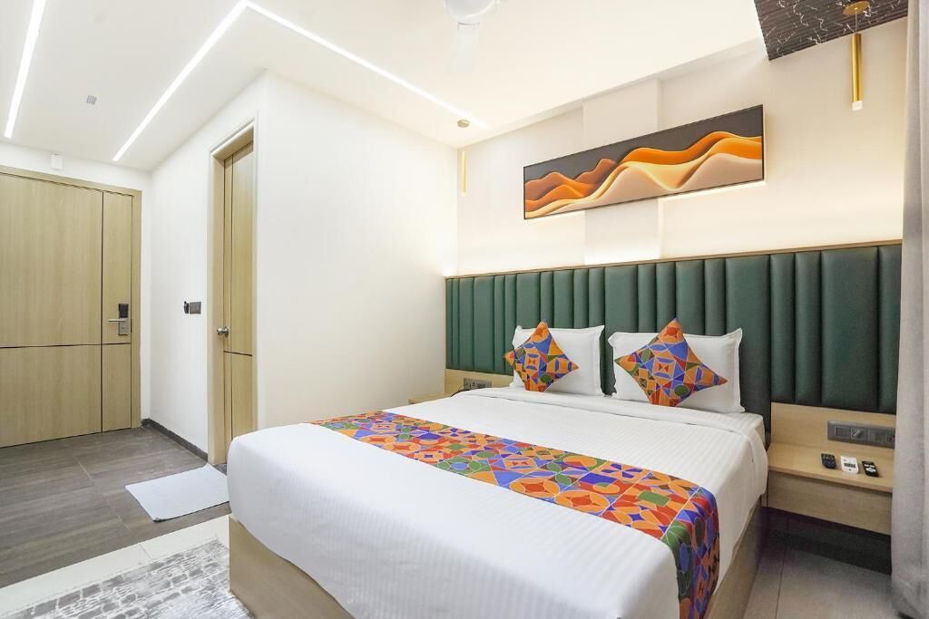 Una habitación de hotel con una cama, cabecero, una obra de arte en la pared, mesita de noche y armario.