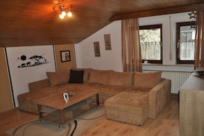Ein gemütliches Wohnzimmer mit einer Eckcouch, einem Couchtisch und einer Heizung.