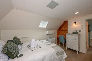 A bedroom with a bed, a dresser, a chair, a small table, an air conditioning unit, and a window with blinds. - Holly House, your Portal to Mt. Shasta Bliss. (Mount Shasta)