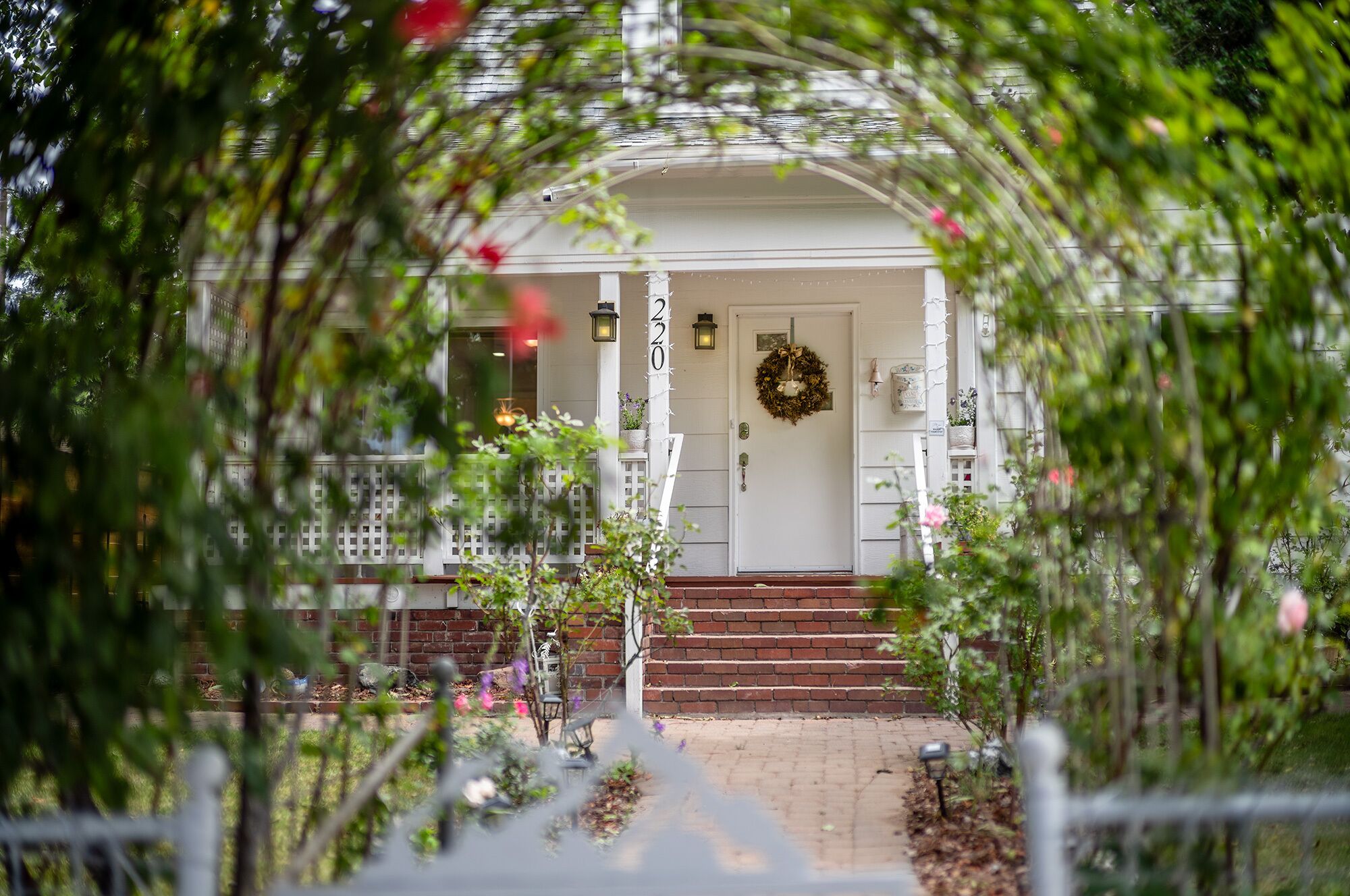 A white house with a front door, a number '220' on the wall, and a brick staircase leading up to the door.