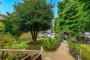 A pathway leading through a garden with trees and a brick wall. - Holly House, your Portal to Mt. Shasta Bliss. (Mount Shasta)