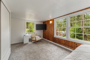 A bedroom with a large window, a desk, a chair, and a bed. - The Hemlock House | The Disconnect Cabin (Dunsmuir)