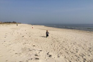 A sandy beach with footprints and a child walking. - Dräger's Holmkjer-Huus (Gelting)