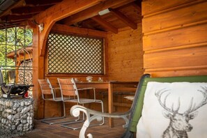 Una baita in legno con angolo ristoro, barbecue e una testa di cervo decorativa.