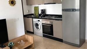 A modern kitchen with a washing machine, oven, and refrigerator.