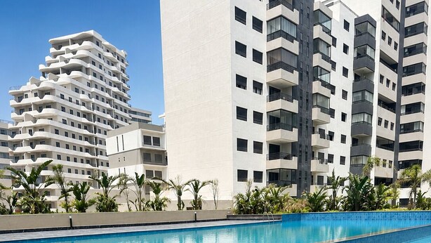 A swimming pool with a tiled edge, surrounded by a landscaped area with palm trees.