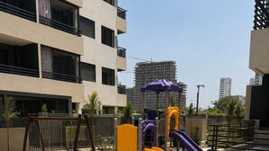 A playground with slides and swings, surrounded by a landscaped area with plants and a bench.