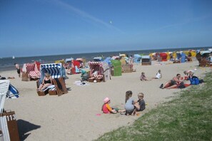 A beach with beach chairs and umbrellas, a sandy area, and a grassy slope. - Jade View, Ground Floor (Varel\/Dangast)