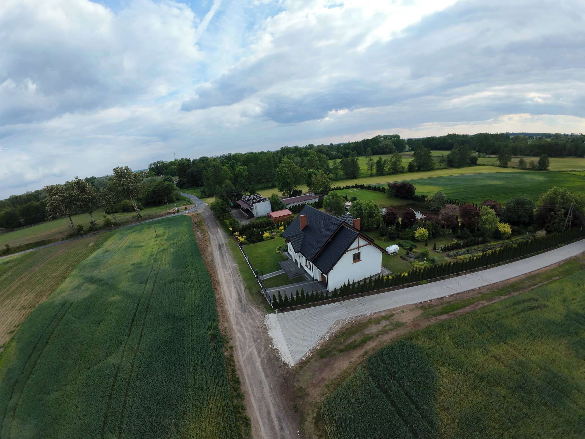 Una propiedad rural con una casa grande, campos verdes extensos y cielo despejado.