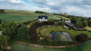 Ein großzügiges Haus, umgeben von einem gepflegten Garten mit Teich und ordentlich geschnittenen Hecken.