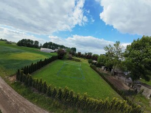 Un paisaje rural con un campo verde, una zona cercada y un edificio pequeño.