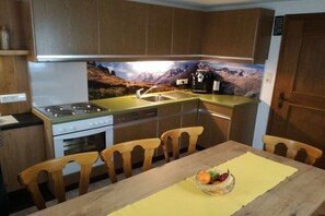 Eine kleine Küche mit Holzausstattung, einem Herd, einem Spülbecken und einem Esstisch mit St ühlen.