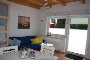 A room with a blue sofa, white table, and a painting on the wall. - Holiday home Weideneck 1 (Kühlungsborn)