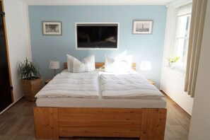A room with a bed, a TV, and two framed pictures on the wall. - Holiday apartment with 1 bedroom (Warnemünde)