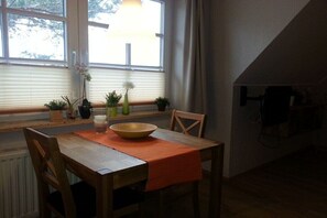 Ein Essbereich mit Tisch, Stühlen, einer Schüssel und Topfpflanzen.