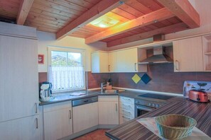 Eine kleine Küche mit Holzbalken, einem Fenster, einer Spüle, einem Herd und einem Toaster.