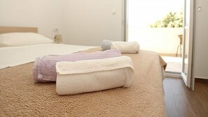 Un dormitorio con una cama, dos toallas enrolladas, una mesita de noche y un ventanal corredero que da a un área exterior.