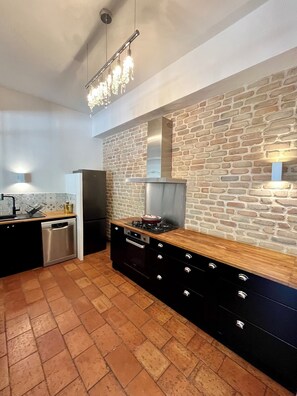 Una cocina con pared de ladrillo, electrodomésticos de acero inoxidable y encimera de madera.