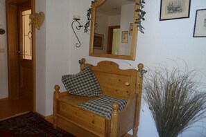 Ein hölzernes Bett mit karierten Kissen, ein Spiegel darüber und eine Pflanze daneben.