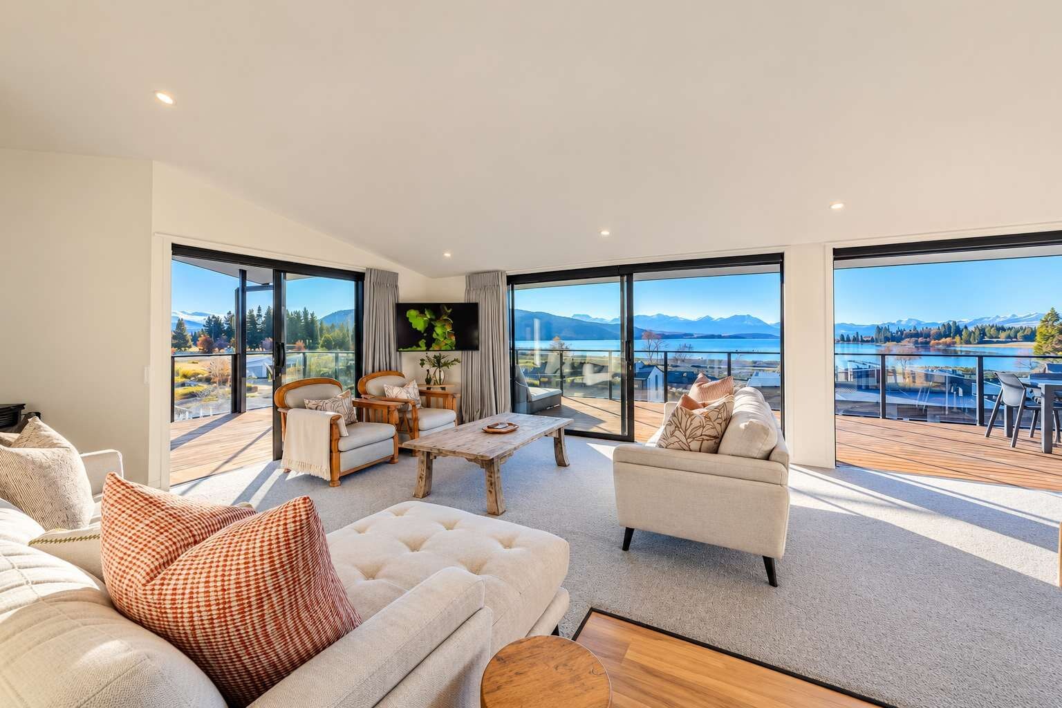 A spacious living room with a large window offering a scenic view of mountains and a lake.
