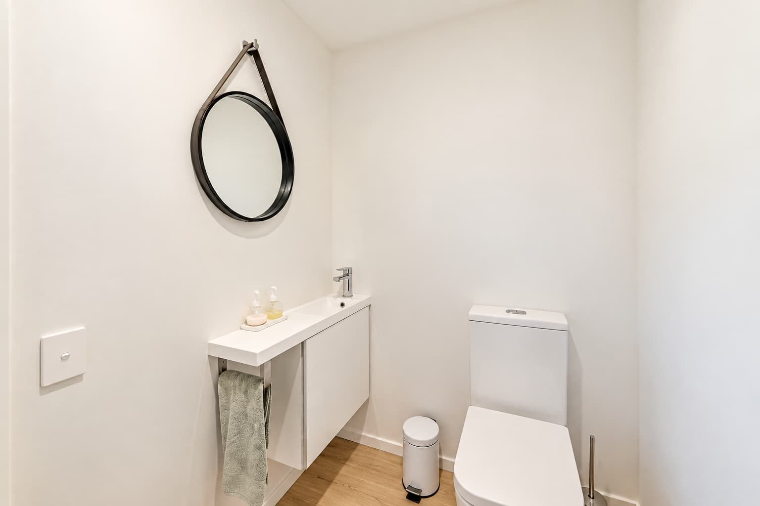 A small, white bathroom with a toilet, a sink, and a mirror.