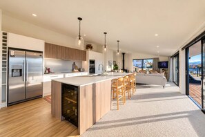 A modern kitchen with a central island, stainless steel appliances, and a large window offering a view. - The Lookout | Tekapo Lake Views | Sleeps 6 (Lake Tekapo)
