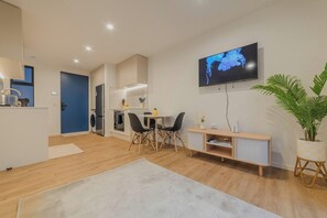 Ein modernes Wohnzimmer mit Fernseher, Essbereich und Küche.