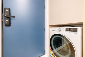 A blue door with a Yale lock and a washing machine with a digital display. - Modern 2BR with Patio | Christchurch CBD (Christchurch)