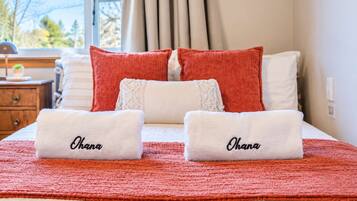 A neatly made bed with two towels labeled 'Ohana' and a red blanket.