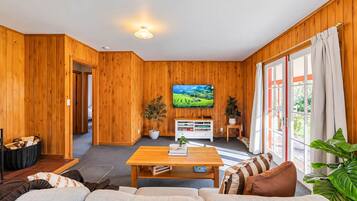 A cozy living room with a wooden interior, a flat-screen TV mounted on the wall, a coffee table, and a sofa.