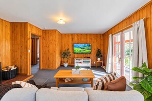 Ein gemütliches Wohnzimmer mit Holzvertäfelung, einem flachbildfernseher an der Wand, einem Couchtisch und einem Sofa.