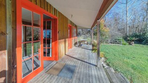 Un bâtiment en bois avec des fenêtres à cadre rouge et un porche couvert.