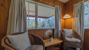 Une pièce chaleureuse avec deux fauteuils en osier, une petite table sur laquelle est posée une orchidée en pot et une lampe.